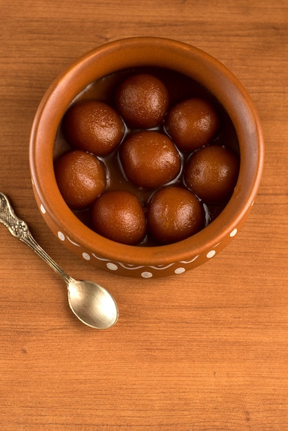 Gulab Jamun in una pentola di terracotta con cucchiaio e frutta secca. Dessert indiano o piatto dolce