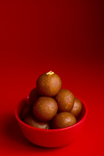 Gulab Jamun nella ciotola rossa su sfondo rosso. Dessert indiano o piatto dolce.
