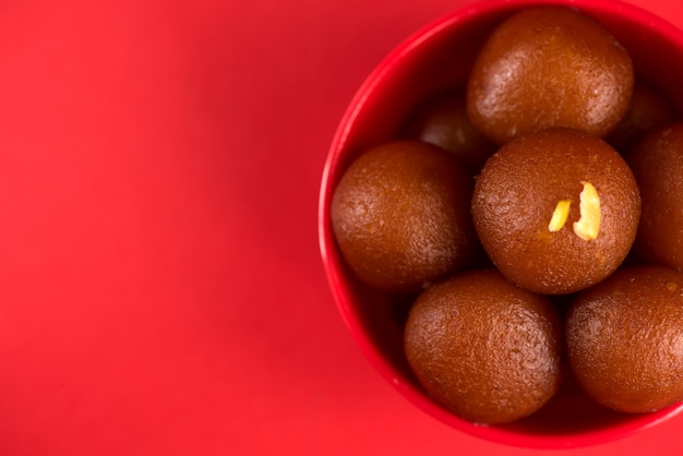 Gulab Jamun nella ciotola rossa sul rosso. Dessert indiano o piatto dolce.