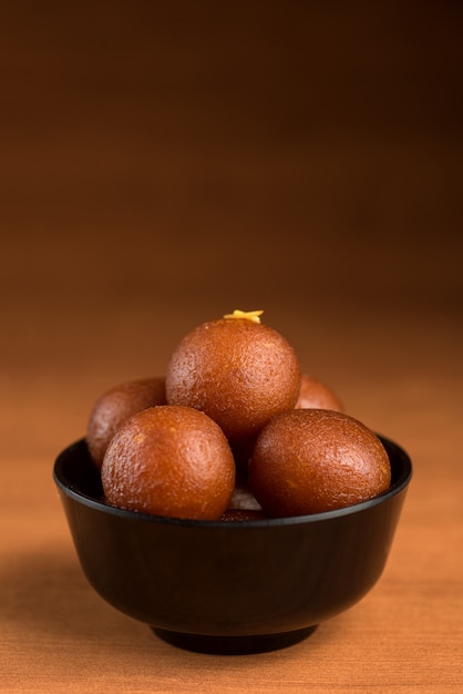 Gulab Jamun nella ciotola su sfondo di legno.