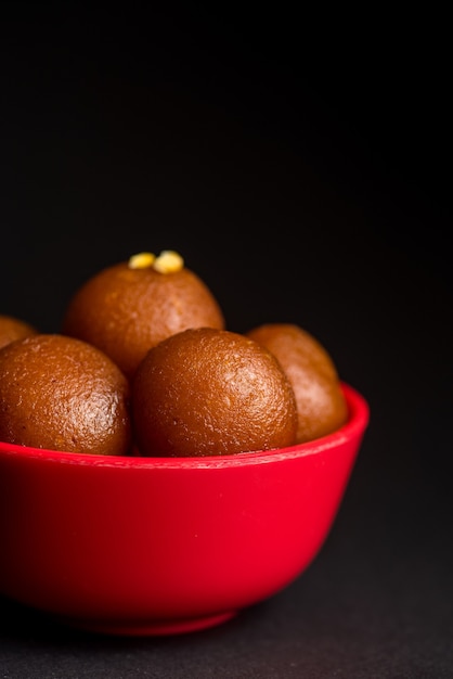 Gulab Jamun nella ciotola su sfondo nero. Dessert indiano o piatto dolce.