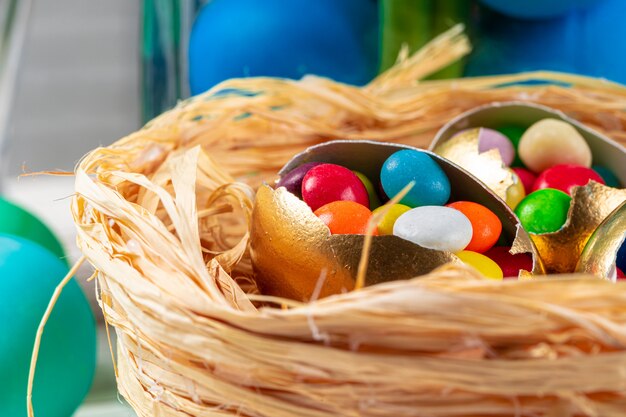 Guscio d'uovo con caramelle colorate all'interno in un nido decorativo di Pasqua