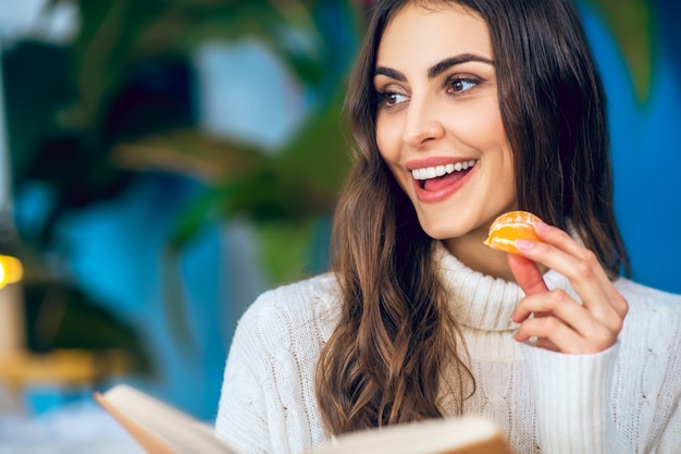 Gusto agrumato. Giovane bella donna che mangia mandarino e che sembra contenta