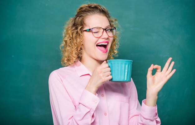 Gusto perfetto. idea e ispirazione. Buon giorno. ragazza rinfrescante con bevanda al tè. donna con la tazza di caffè alla lavagna. energia e vigore. carica energetica. l'insegnante di scuola ha bisogno di una pausa caffè. ok gesto.