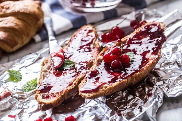 Gustosa colazione con croissant alla marmellata di ribes rosso burro e foglie di menta.