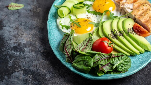 Gustosa colazione con uova fritte con pomodorini avocado filetto di pollo alla griglia cetrioli e avocado Colazione sana vista dall'alto