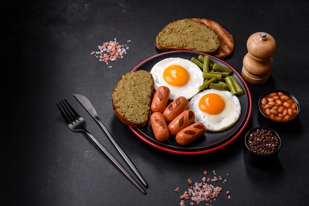 Gustosa colazione inglese a base di uova fritte, fagioli, asparagi, salsicce con spezie ed erbe aromatiche