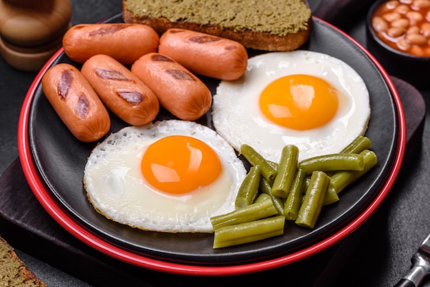 Gustosa colazione inglese a base di uova fritte, fagioli, asparagi, salsicce con spezie ed erbe aromatiche