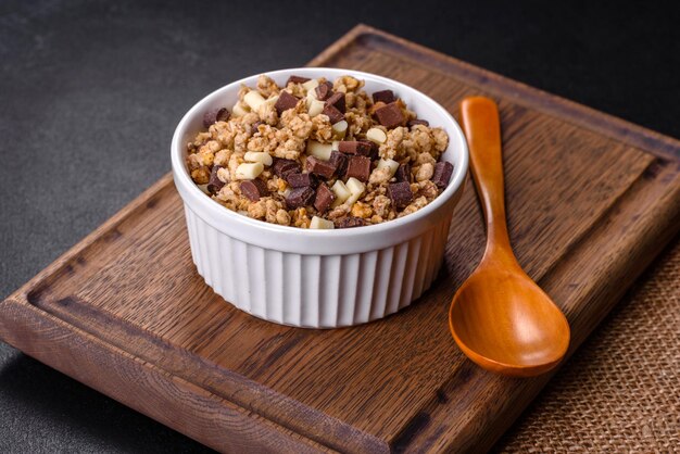 Gustosa colazione sana con cereali muesli cioccolato latte e marmellata su uno sfondo di cemento scuro