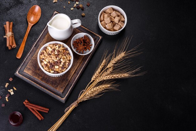 Gustosa colazione sana con cereali muesli cioccolato latte e marmellata su uno sfondo di cemento scuro