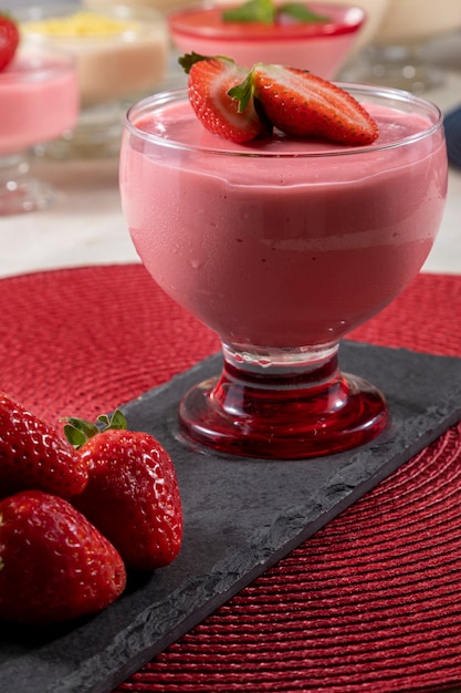 Gustosa mousse alla fragola in vetro con sopra la fragola.