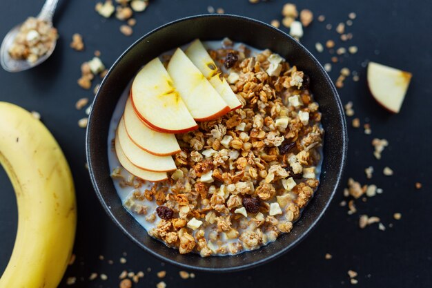 Gustosa muesli fruttata fatta in casa servita in una ciotola su sfondo scuro. Avvicinamento