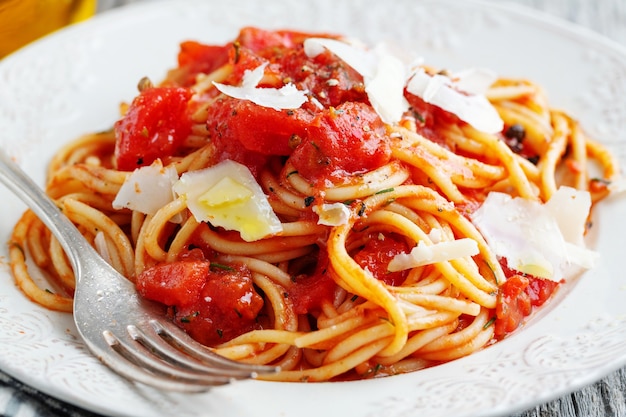 Gustosa pasta italiana classica con salsa di pomodoro e formaggio sul piatto. Avvicinamento.