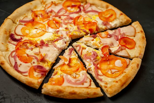gustosa pizza con prosciutto, pomodoro, peperoncino, salsa di pomodoro, mozzarella su uno sfondo di pietra