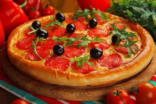 Gustosa pizza con salame sulla tavola di legno decorata da vicino