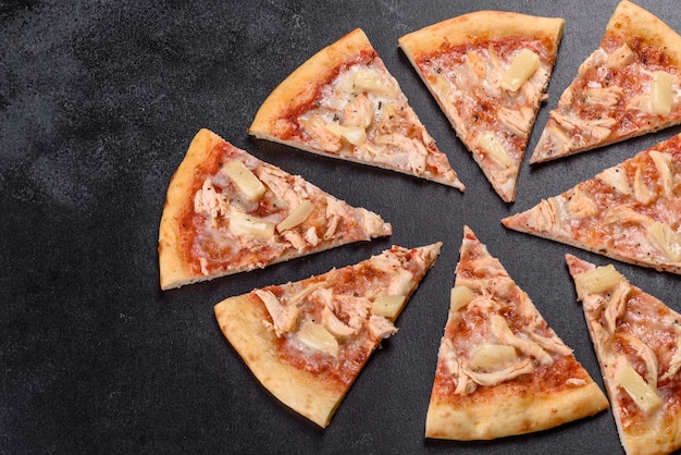 Gustosa pizza fresca al forno con pomodori, formaggio e ananas su uno sfondo di cemento scuro
