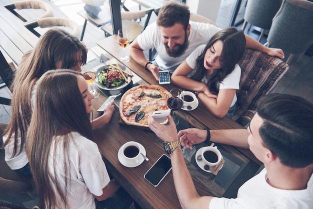 Gustosa pizza sul tavolo, con un gruppo di giovani sorridenti che riposano nel pub