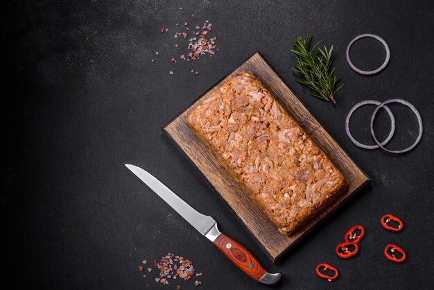 Gustosa soppressata di carne o rotolo su un tagliere di legno con spezie ed erbe aromatiche