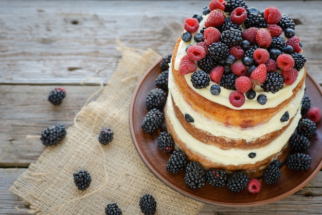 Gustosa torta con fragole, lamponi e mora su un tavolo di legno