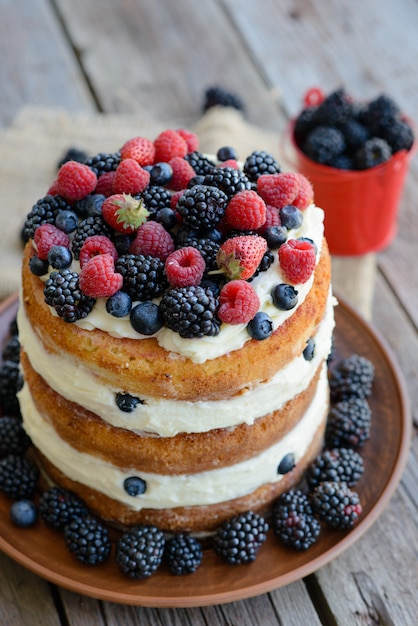 Gustosa torta con fragole, lamponi e mora su un tavolo di legno