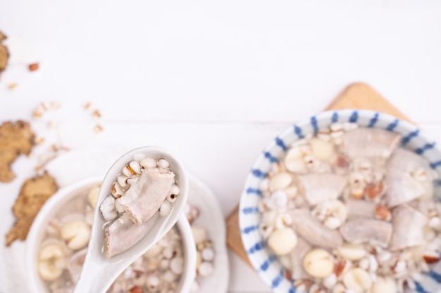 Gustosa zuppa di erbe aromatiche ai quattro tonici, cibo tradizionale taiwanese con erbe aromatiche, intestini di maiale su tavolo di legno bianco, primo piano, piatto, vista dall'alto.