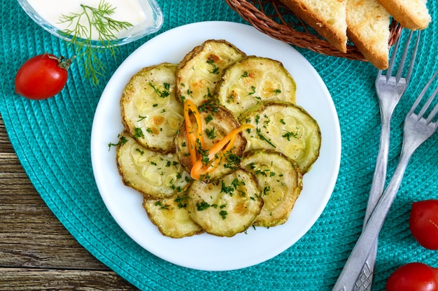 Gustose fette di zucchine fritte su un piatto con salsa su un tavolo di legno. Merenda picnic. Stile rustico. Vista dall'alto, piatto.