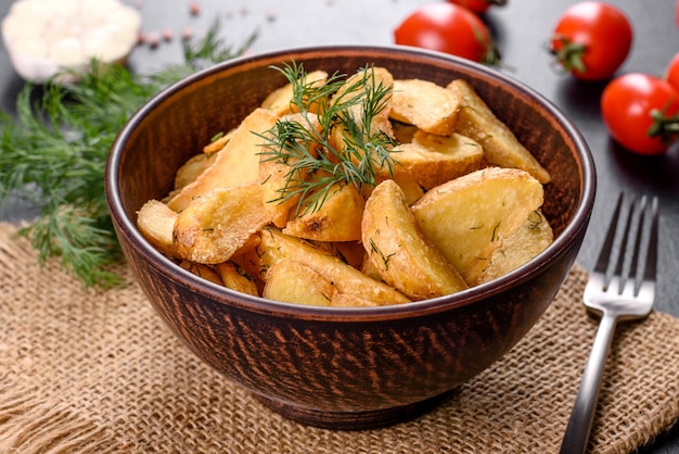 Gustose patate al forno in modo rustico con spezie ed erbe aromatiche in un piatto fondo marrone. Cibo malsano