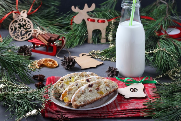 Gustose stollen natalizie a fette con frutta secca e bottiglia di latte. Trattare per Babbo Natale. Composizione di Natale. Formato orizzontale