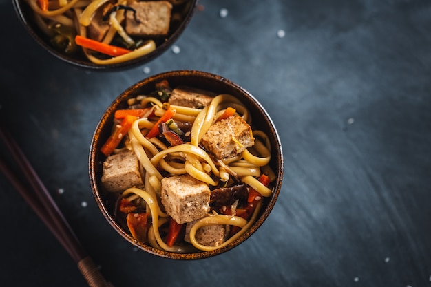 Gustose tagliatelle asiatiche con formaggio tofu e verdure su piatti.