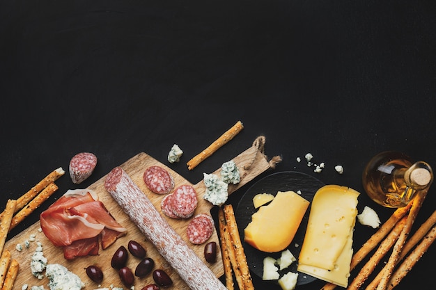 Gustosi antipasti italiani classici su sfondo scuro. Vista dall'alto.