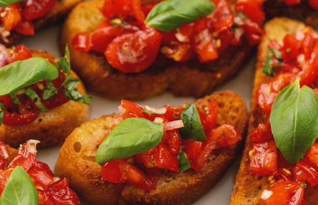 Gustosi antipasti italiani di pomodoro salato o bruschette su fette di baguette tostate guarnite con basilico