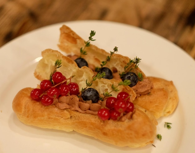 Gustosi bignè francesi con glassa di frutti di bosco freschi ed elementi decorativi di zucchero