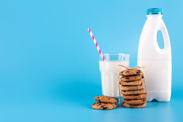 Gustosi biscotti al cacao con gocce di cioccolato Una bottiglia e un bicchiere di latte isolato su sfondo blu