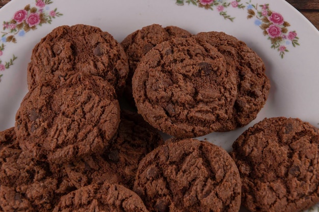 Gustosi biscotti al cioccolato su piatto bianco su sfondo di legno Fuoco selettivo