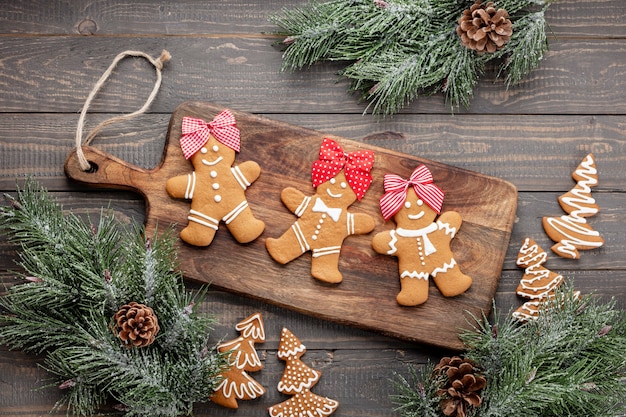 Gustosi biscotti di panpepato e decorazioni natalizie su fondo di legno.