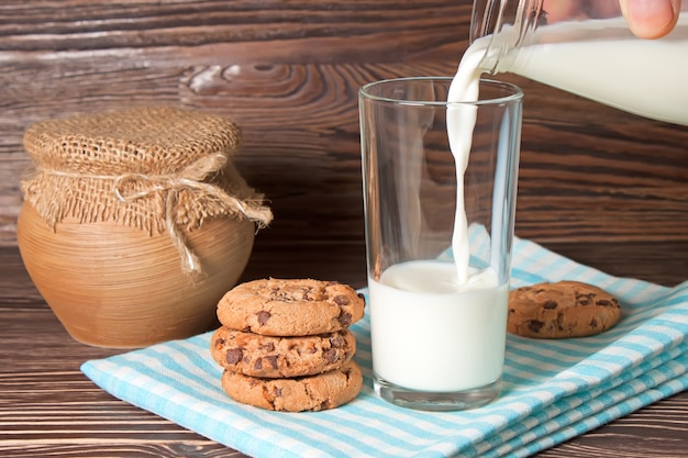 Gustosi biscotti e bicchiere di latte su fondo di legno rustico