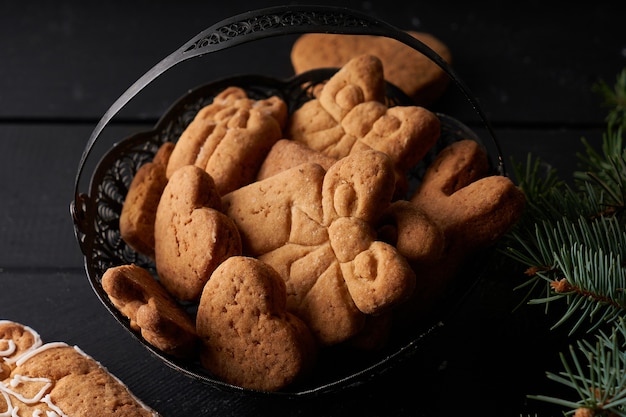 Gustosi biscotti fatti in casa con glassa sul tavolo scuro con ramo di abete. Concetto di Natale e inverno Close up