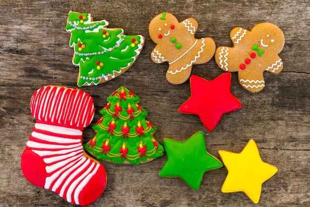 Gustosi biscotti natalizi festivi a forma di albero di Natale, omino di pan di zenzero, stella e calzino natalizio su tavola in legno rustico. Vista dall'alto