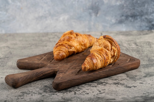 Gustosi croissant burrosi posti su un tagliere di legno.