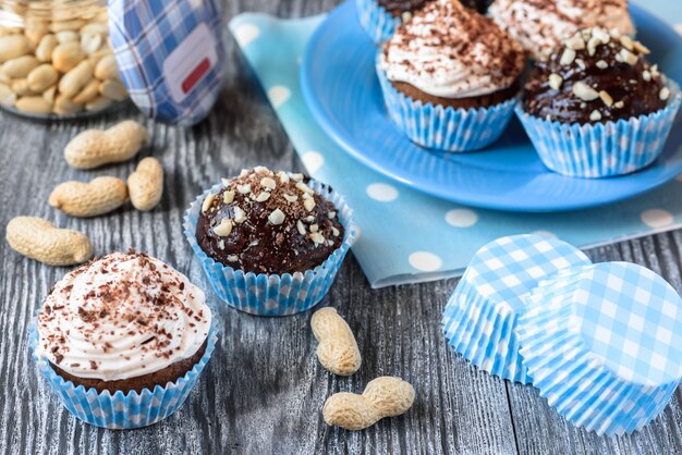 Gustosi cupcakes al cioccolato su uno sfondo di legno grigio con cioccolato e noci