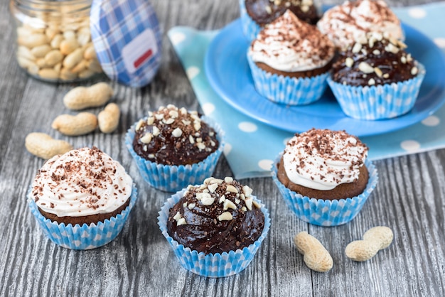 Gustosi cupcakes al cioccolato su uno sfondo di legno grigio con cioccolato e noci