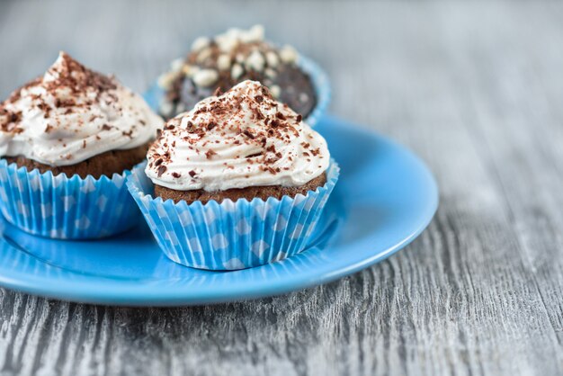 Gustosi cupcakes al cioccolato su uno sfondo di legno grigio con cioccolato