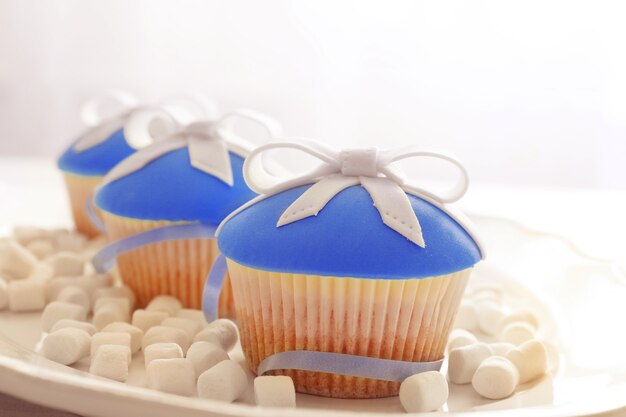 Gustosi cupcakes con fiocco e giocattoli di Natale su fondo in legno colorato