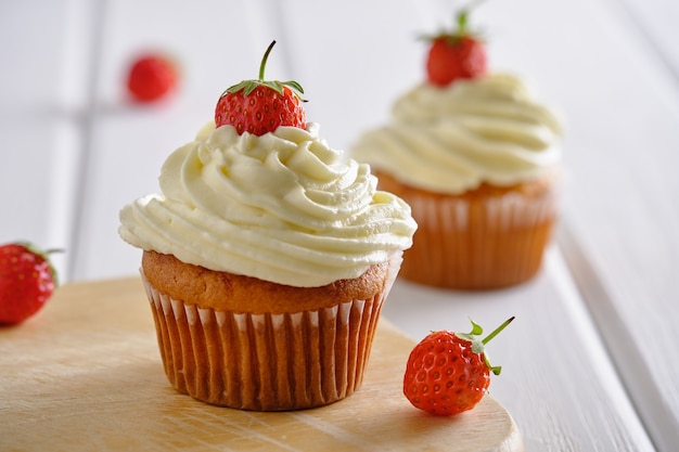 Gustosi cupcakes con fragole e crema delicata su sfondo bianco