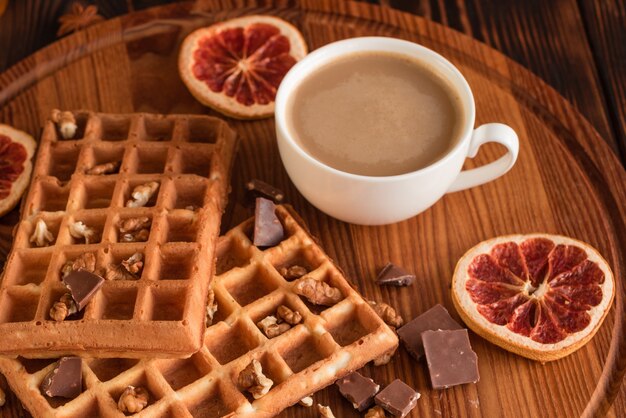 Gustosi freschi wafer di Vienna, marmellata e tazza di caffè su uno sfondo di legno scuro