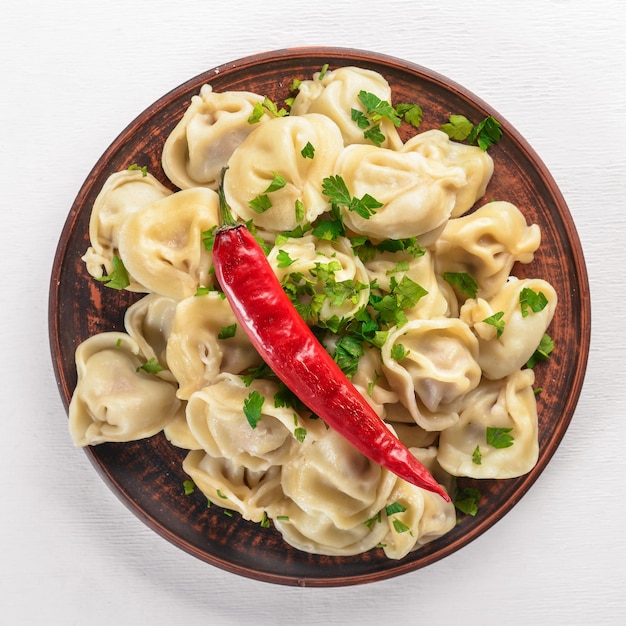 Gustosi gnocchi di carne fatti in casa di farina integrale o pelmeni russi cosparsi di prezzemolo fresco sul piatto su tavola di legno spazio copia vista dall'alto