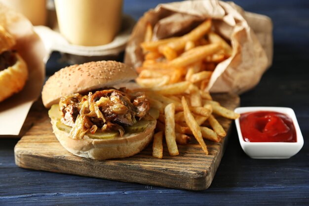 Gustosi hamburger e patatine fritte su piatto su sfondo tavolo in legno Concetto di cibo malsano