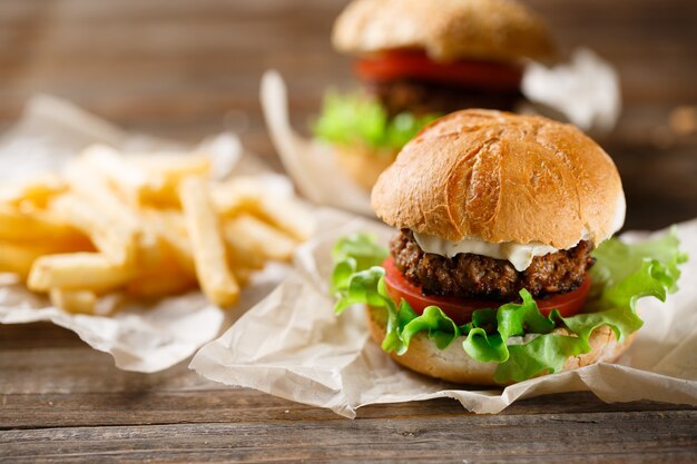 Gustosi hamburger fatti in casa e patatine fritte sul tavolo di legno