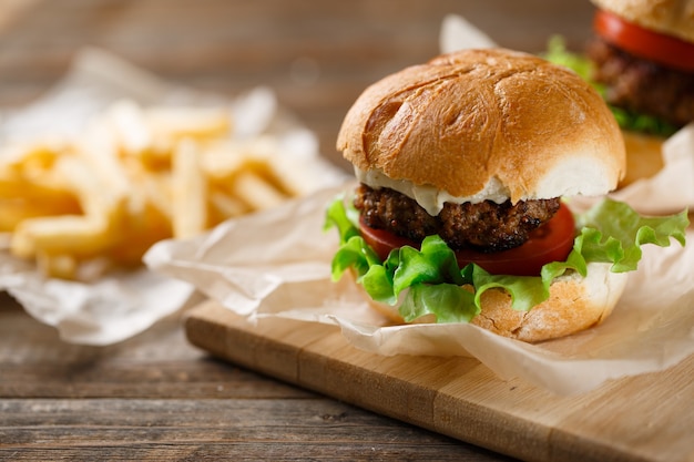 Gustosi hamburger fatti in casa e patatine fritte sul tavolo di legno