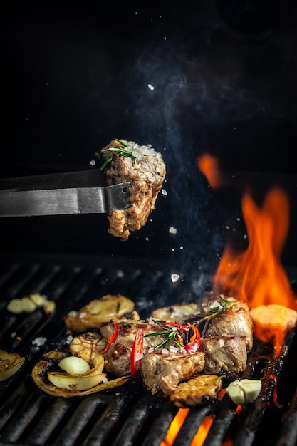 Gustosi pezzi di carne alla griglia e fiamma sulla griglia